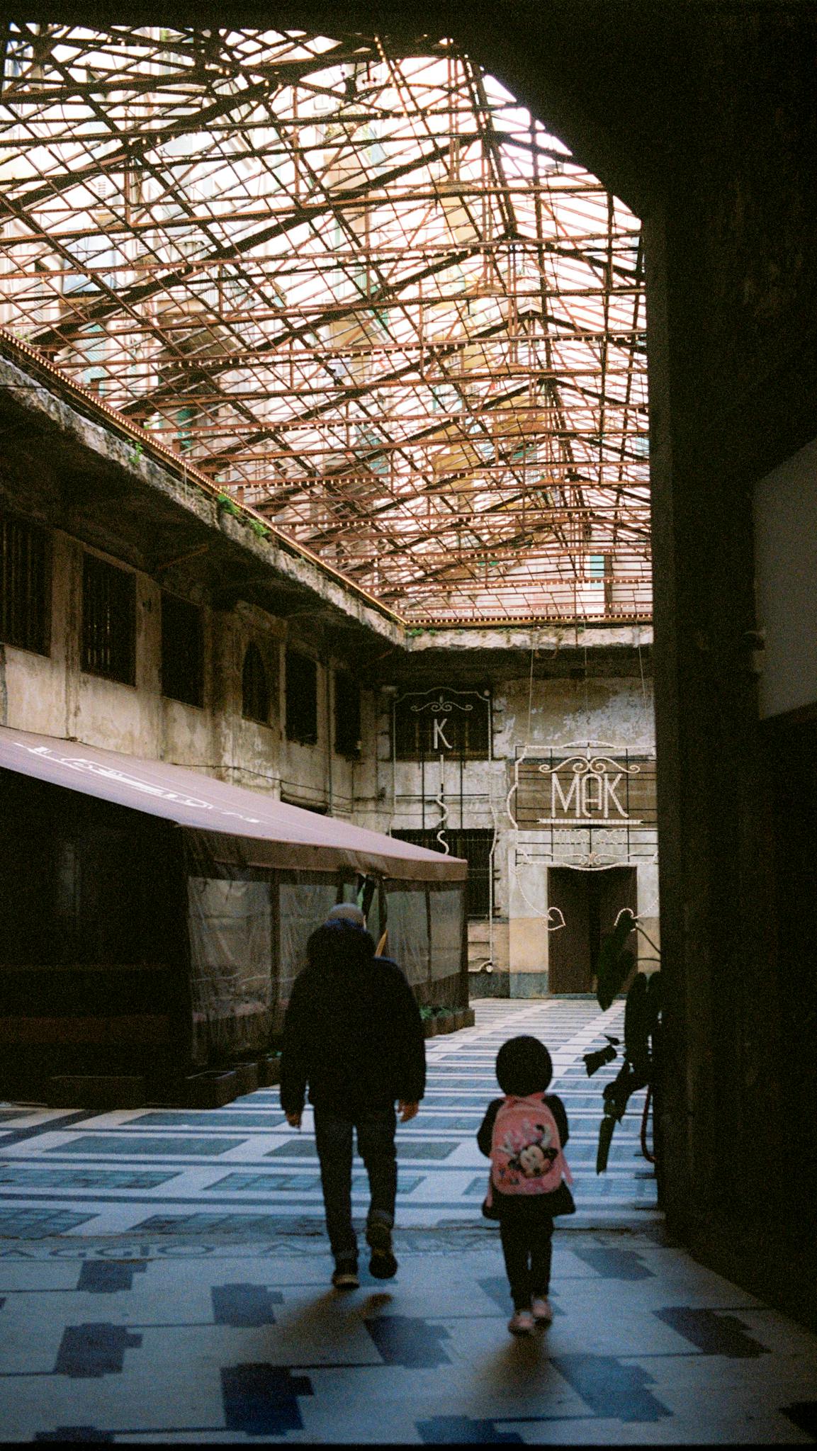 A man and child walk through a rustic passageway in Palermo, Italy.