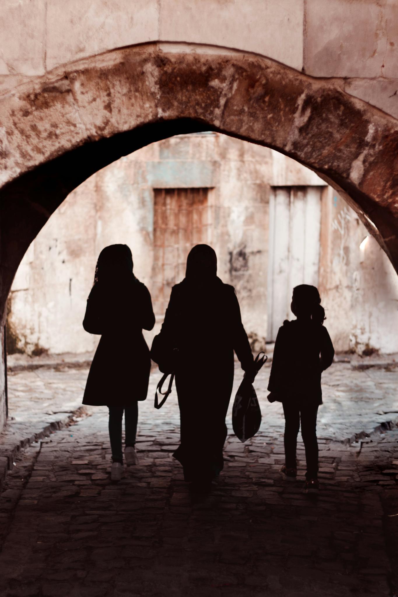Silhouetted family walking through a historic stone tunnel, creating a mysterious and timeless scene.